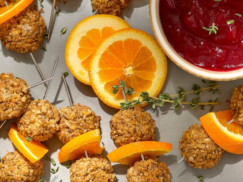 Savory Vegan Meatballs on a serving platter with a side dish of Cranberry Glaze