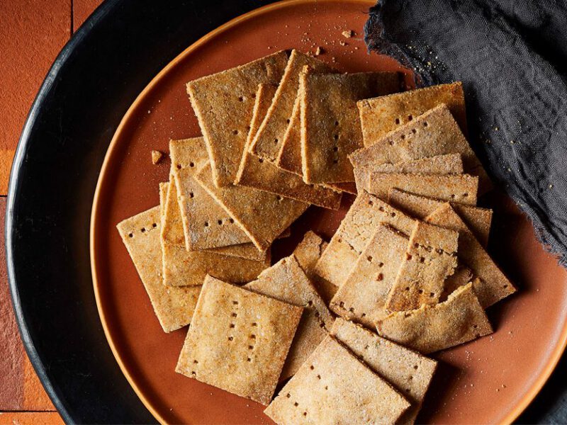 Vegan Cheesy Crackers on a brown plate next to a gray cloth napkin