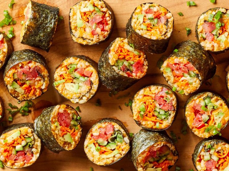 spicy tomato sushi rolls on a wooden cutting board with chopsticks in the right corner