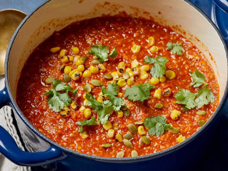 A bright-colored roasted red pepper stew, sprinkled with cilantro, in a blue pot
