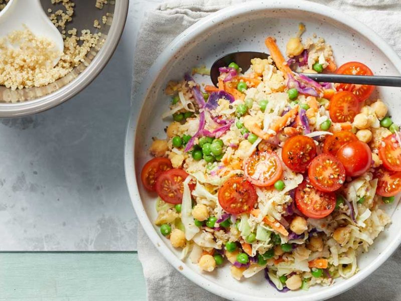 15-Minute Quinoa Slaw Bowl in a white dish with a metal spoon