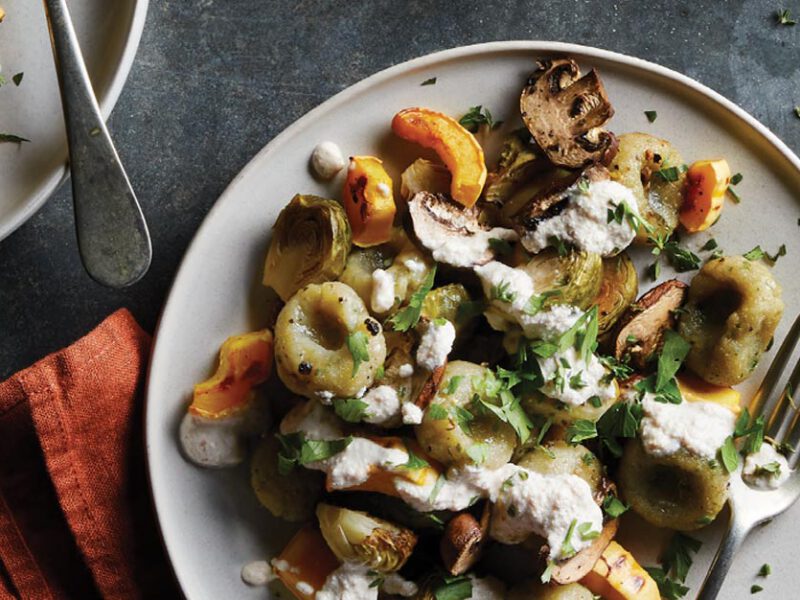 Gluten-Free Gnocchi with Roasted Vegetables on a white plate with metal fork and orange napkin