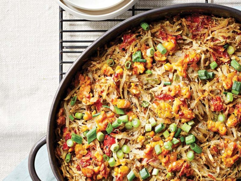 Vegan Hash Brown Casserole with Tempeh Crumbles in an oval cast iron skillet on a metal cooling rack