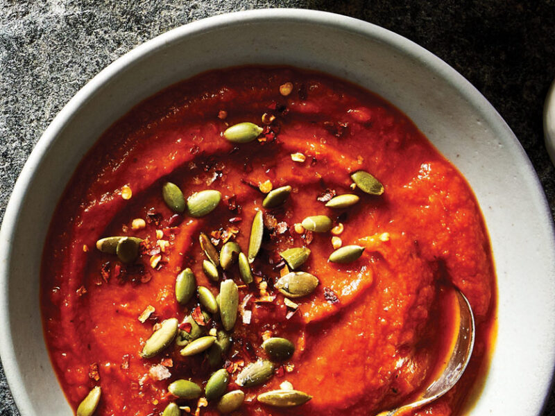 Curried Sweet Potato Soup topped with pumpkin seeds in a white ceramic bowl