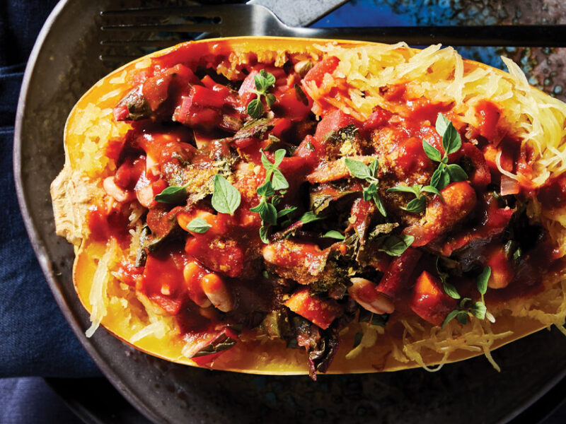 Spaghetti Squash Boats with White Beans and Swiss Chard on a gray ceramic plate against a dark blue tablecloth