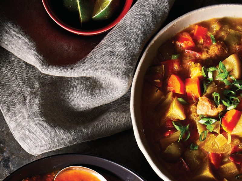 Jamaican Vegetable Stew with Mini Dumplings on a black table next to a grey linen napkin