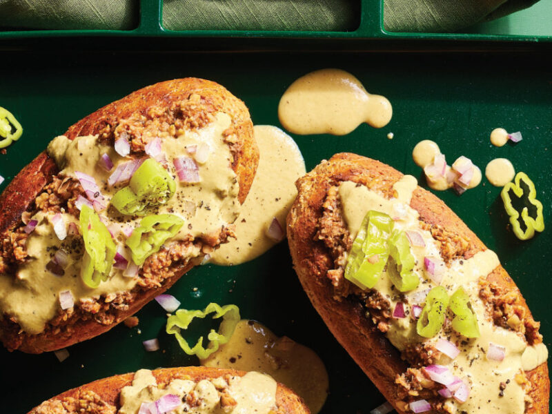 Three Vegan Italian Sausage Grinder Sandwiches topped with a cheesy vegan sauce