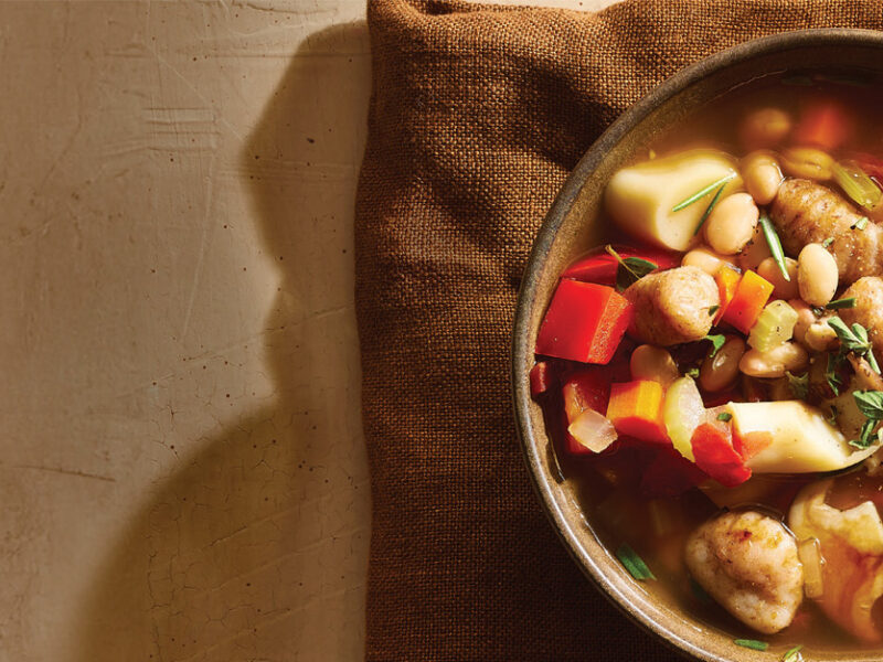 A bowl of Trumpet Mushroom, White Bean and Gnocchi Stew on a brown cloth napkin, ready to eat