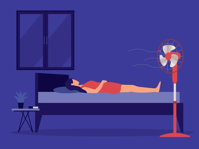 Illustration of woman lying in bed on top of covers with the fan on to combat hot flashes. Deep purple background, lighter figure in an orange dress.