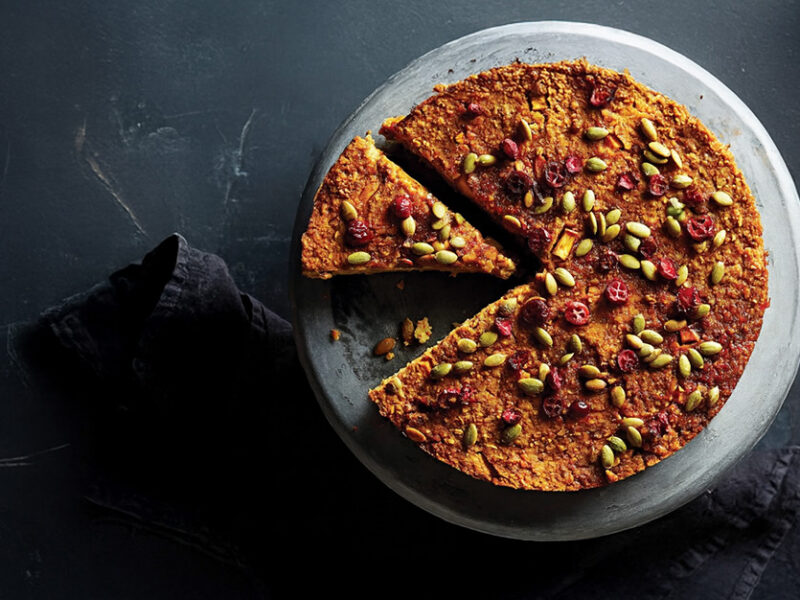 Vegan Holiday Torte on a plate with one sliced cut and ready to be served, on a dark grey background
