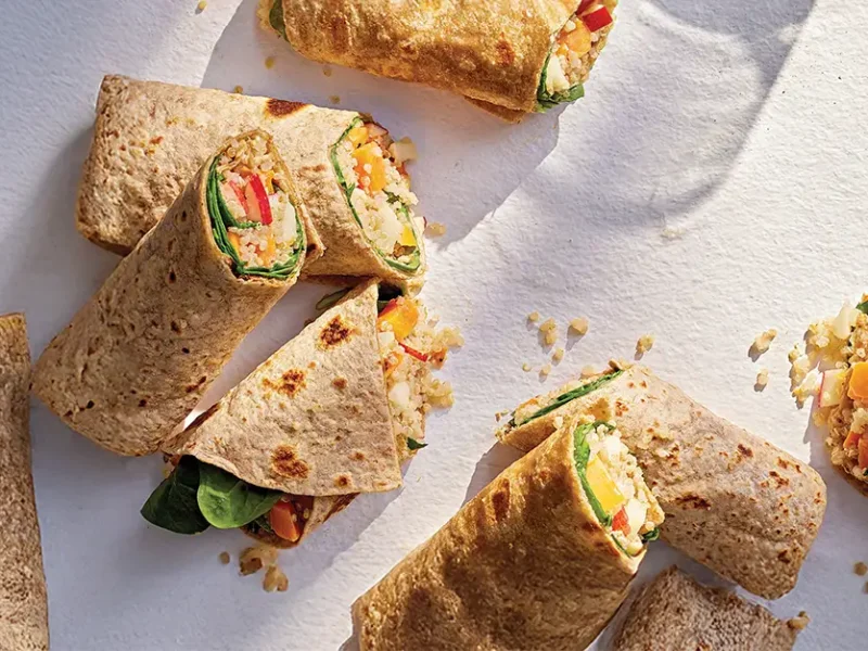 Quinoa, Apple, and Sweet Potato Wraps cut in half on a white counter