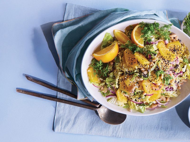 White Bean and Shaved Cabbage Salad with Orange Dressing in white plate on a blue tablecloth