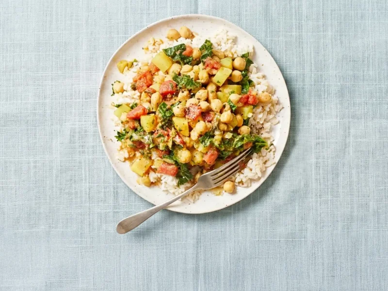Chickpea Curry Stew with Kale on a white plate in a pale blue folded napkin