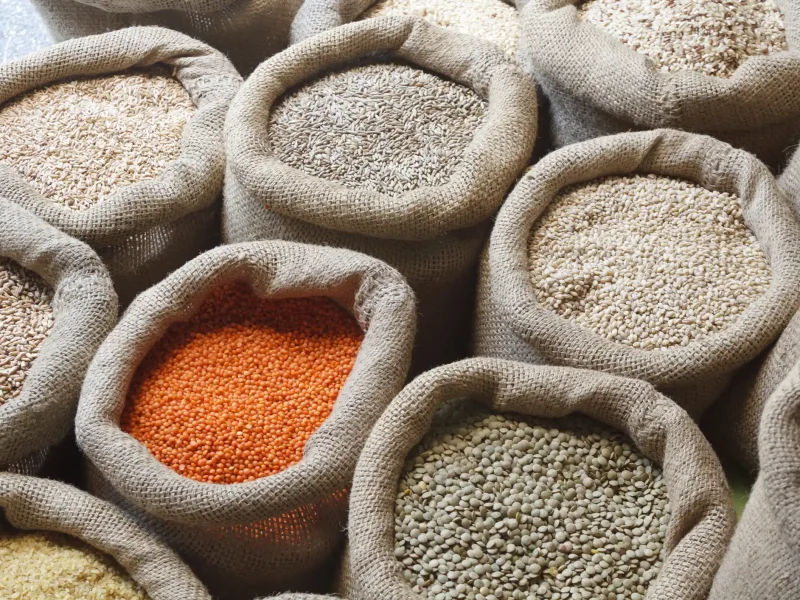 Open-ended sacks of beans and whole grains, including red and brown lentils, rice, and oats