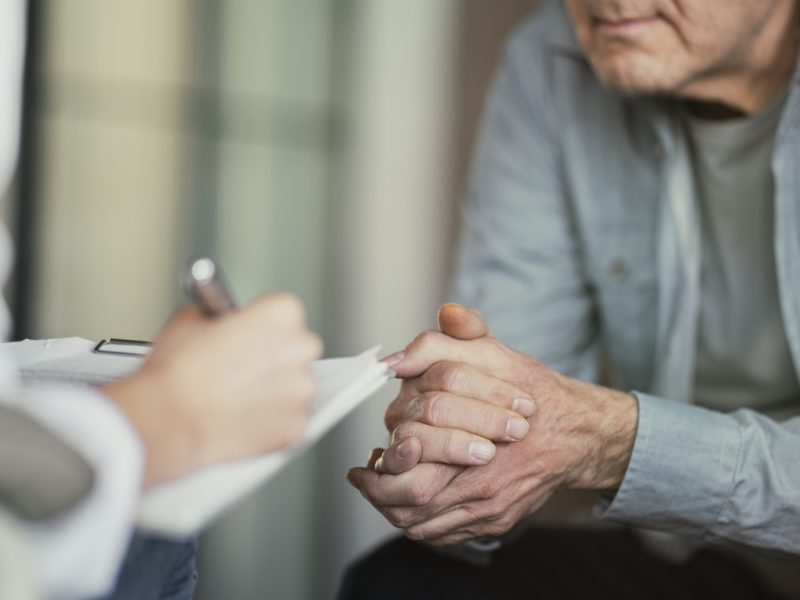 Doctor reviews lab test results with an older male patient during a medical consultation