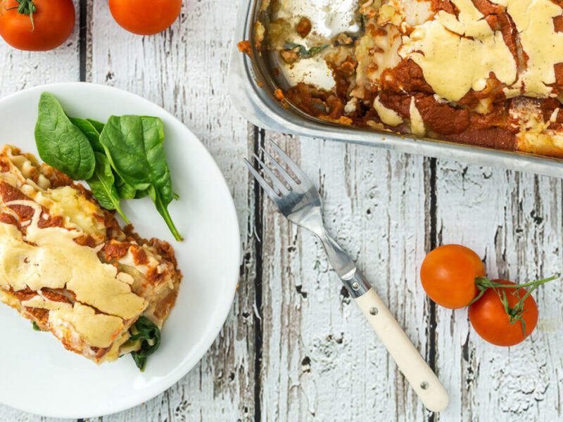 A serving of Sweet Potato Lasagna next to a casserole dish with one serving removed