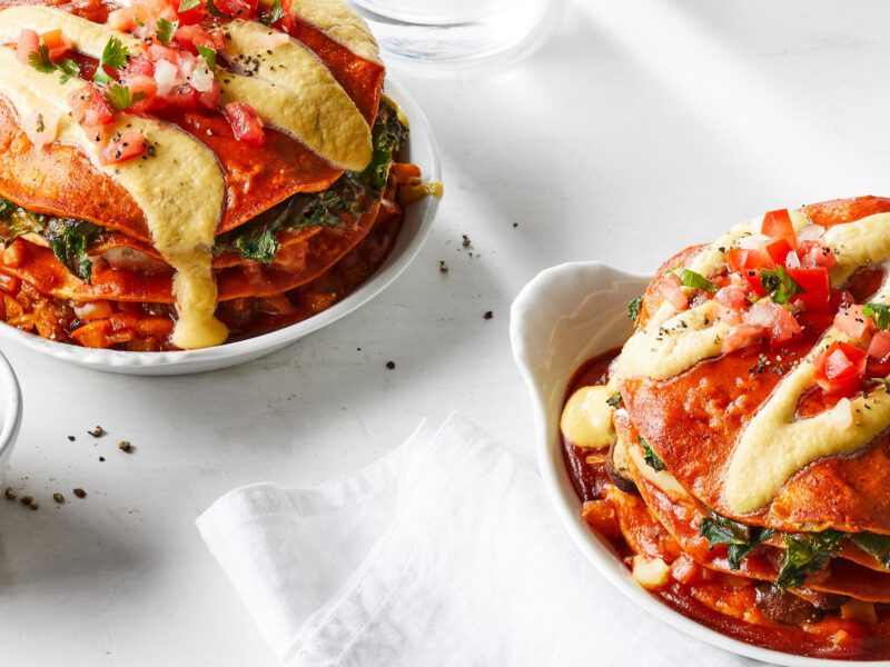 Two stacks of 4-Layer Enchilada Cakes with a small bowl of salsa